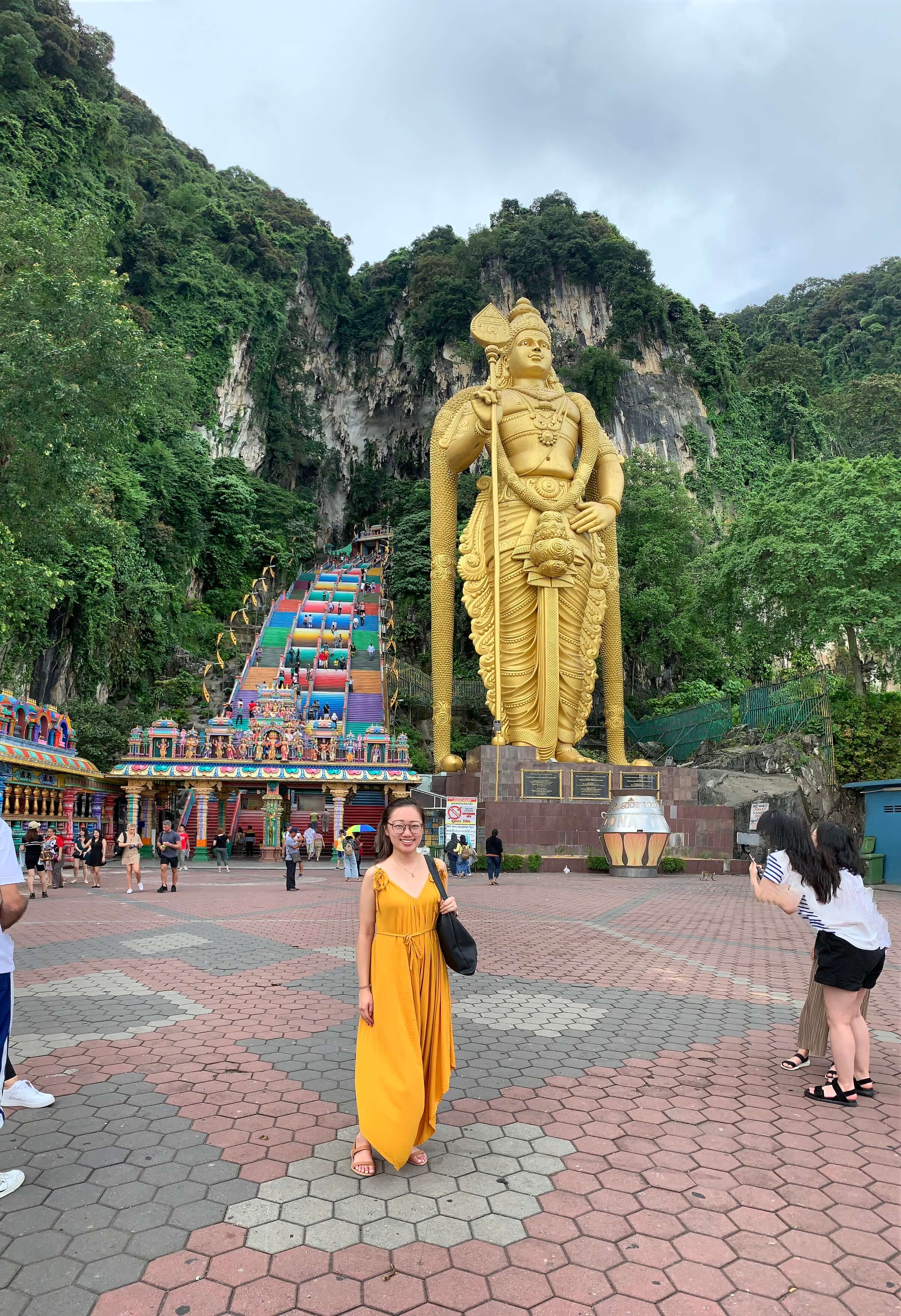 A student in a yellow dress in front of a large golden statue.