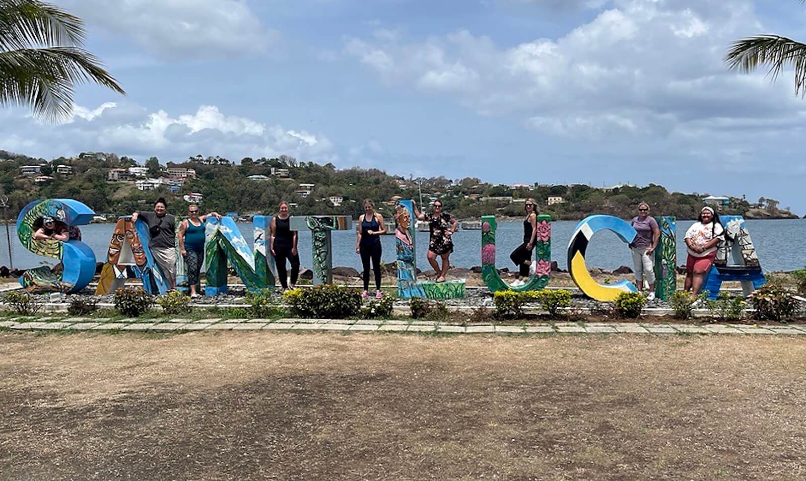A group of students in front of letters at the beachside