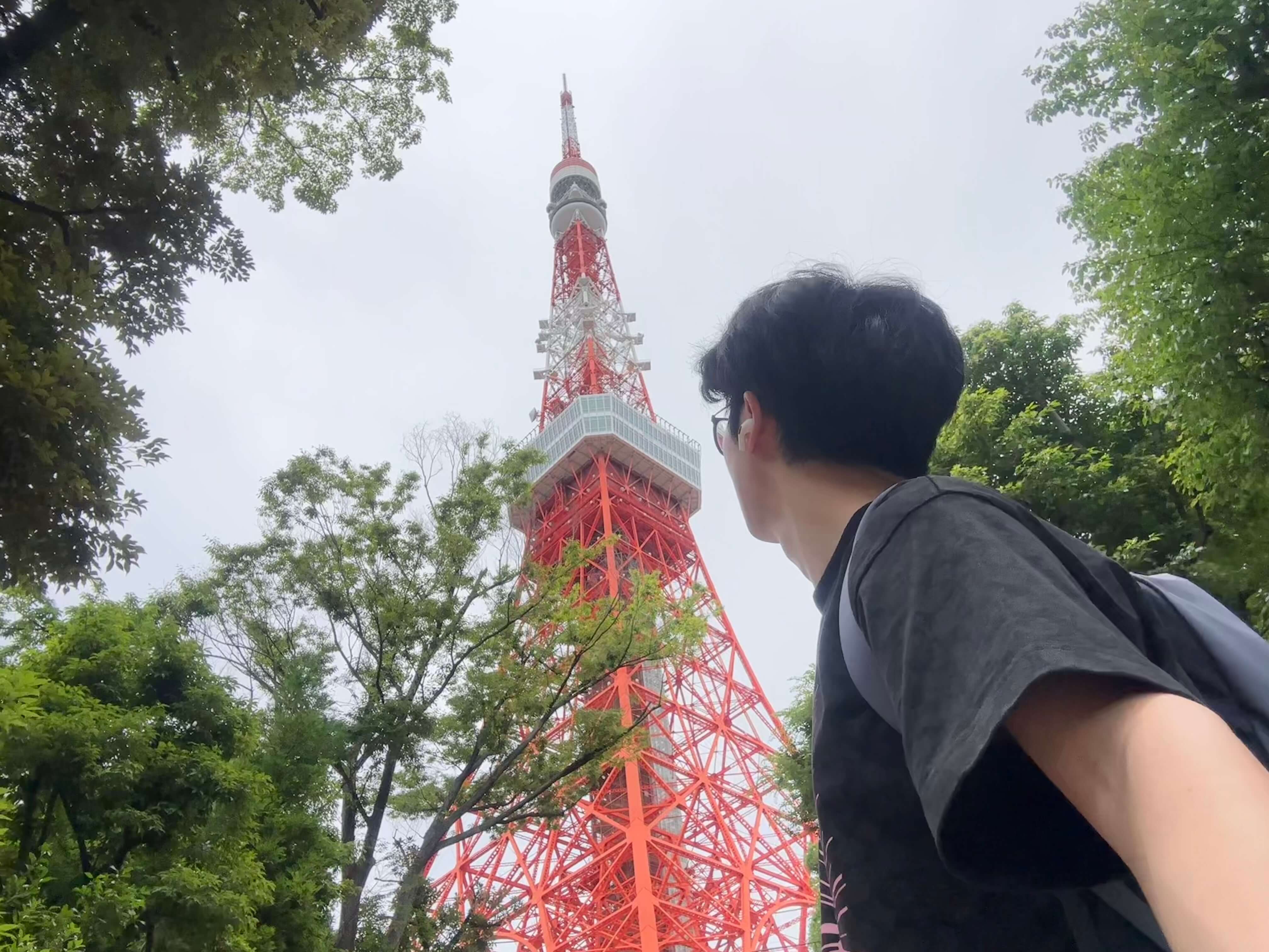 A student looking up at a tall red tower from below.